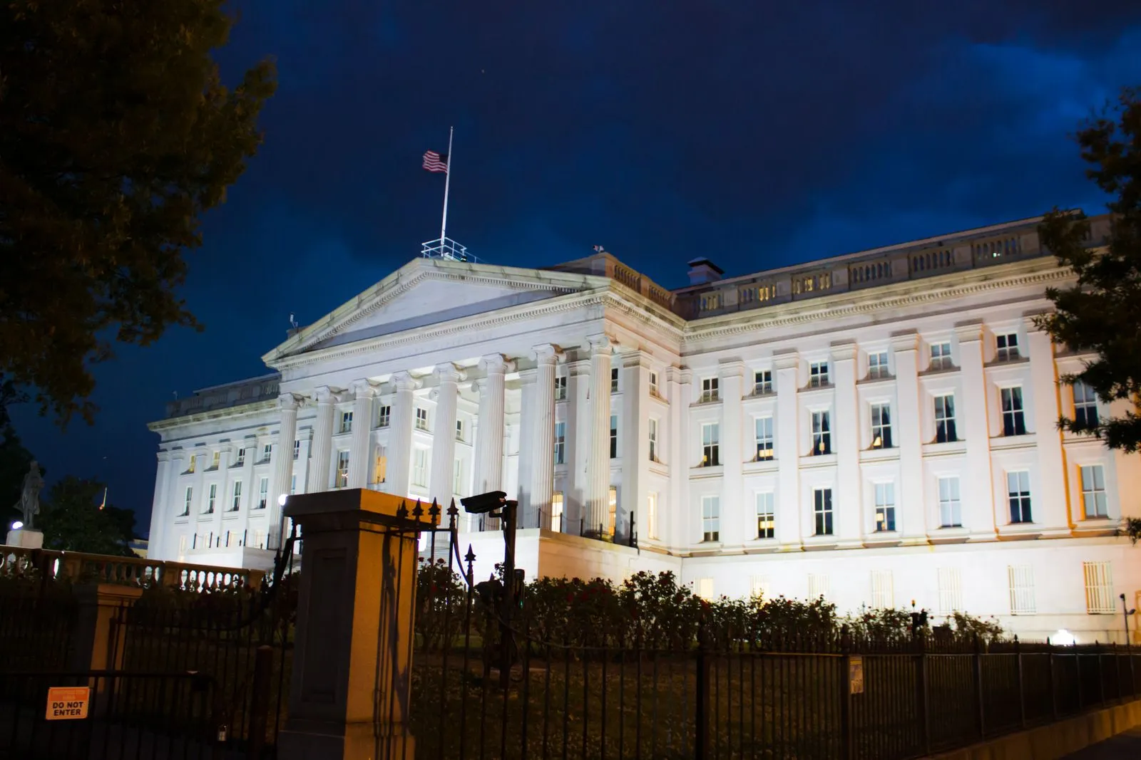 The United States Treasury building in Washington, D.C. lit against a twilight sky.
