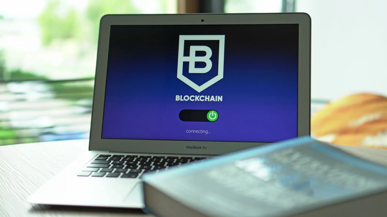 A laptop screen displaying a blockchain application interface with connected network nodes.
